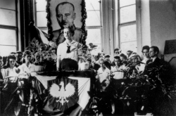 Abiturfeier im "DP"-Lagergymnasium Lippstadt/Westfalen im Jahre 1946. Hinter der Rednerin Radomira Sawaryn hängt umkränzt das Bildnis Wladyslaw Sikorskis, der von 1939 bis zu seinem Tod beim Flugzeugabsturz im Juli 1943 bei Gibraltar Chef der polnischen Exilregierung in London war. Wie auch der gekrönte polnische Adler war Sikorski Symbol des Protestes gegen die Sowjetisierung Polens.