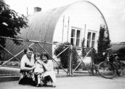 Nissenhütte in Bredstedt 1955. Die in Kanada erfundenen Baracken aus gebogenem Wellblech kamen mit den Alliierten nach dem Zweiten Weltkrieg nach Deutschland. Obwohl in Schleswig-Holstein nicht viele Nissenhütten aufgebaut wurden, sind sie zu einem Symbol der Notzeit nach dem Krieg geworden.