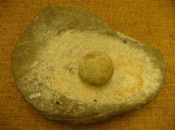 Ein steinzeitlicher Mahltrog: Die Getreidekörner werden auf die Fläche des größeren Steines (meist Granit oder Quarz) gegeben und dann mit einem runden oder ebenen härteren Stein (meist Feuerstein oder Trachyt) zerquetscht oder zerrieben.